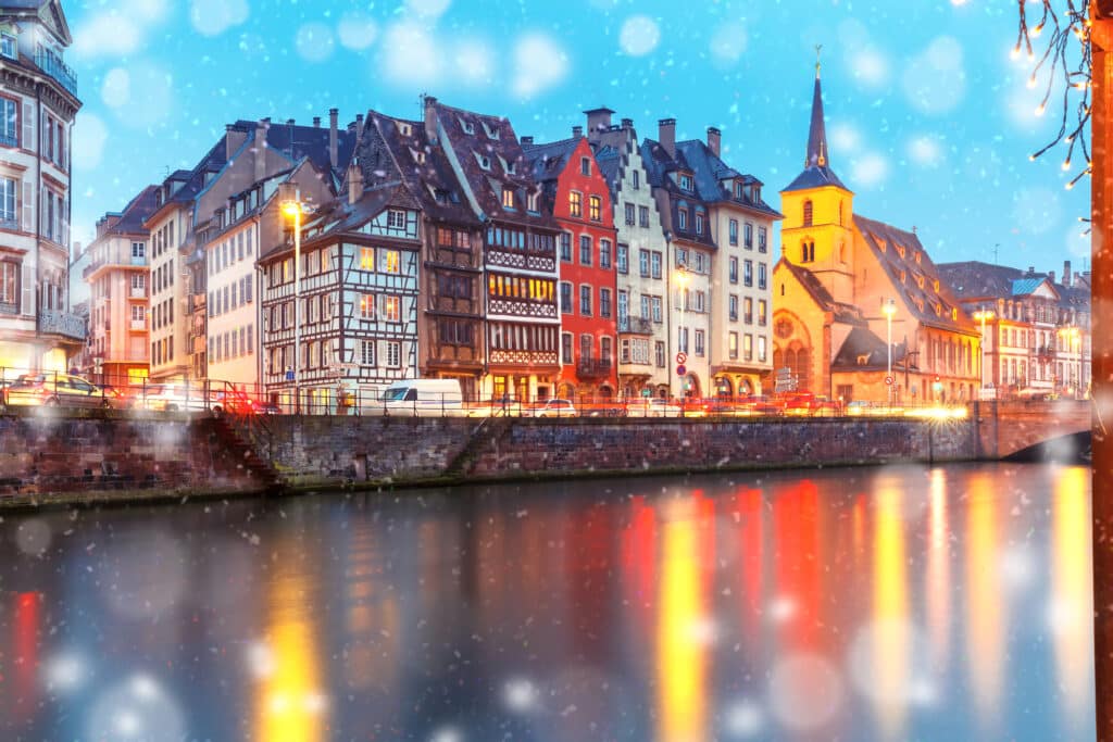 Church of Saint Nicolas and traditional houses during Christmas time with mirror reflections on the river Ill
