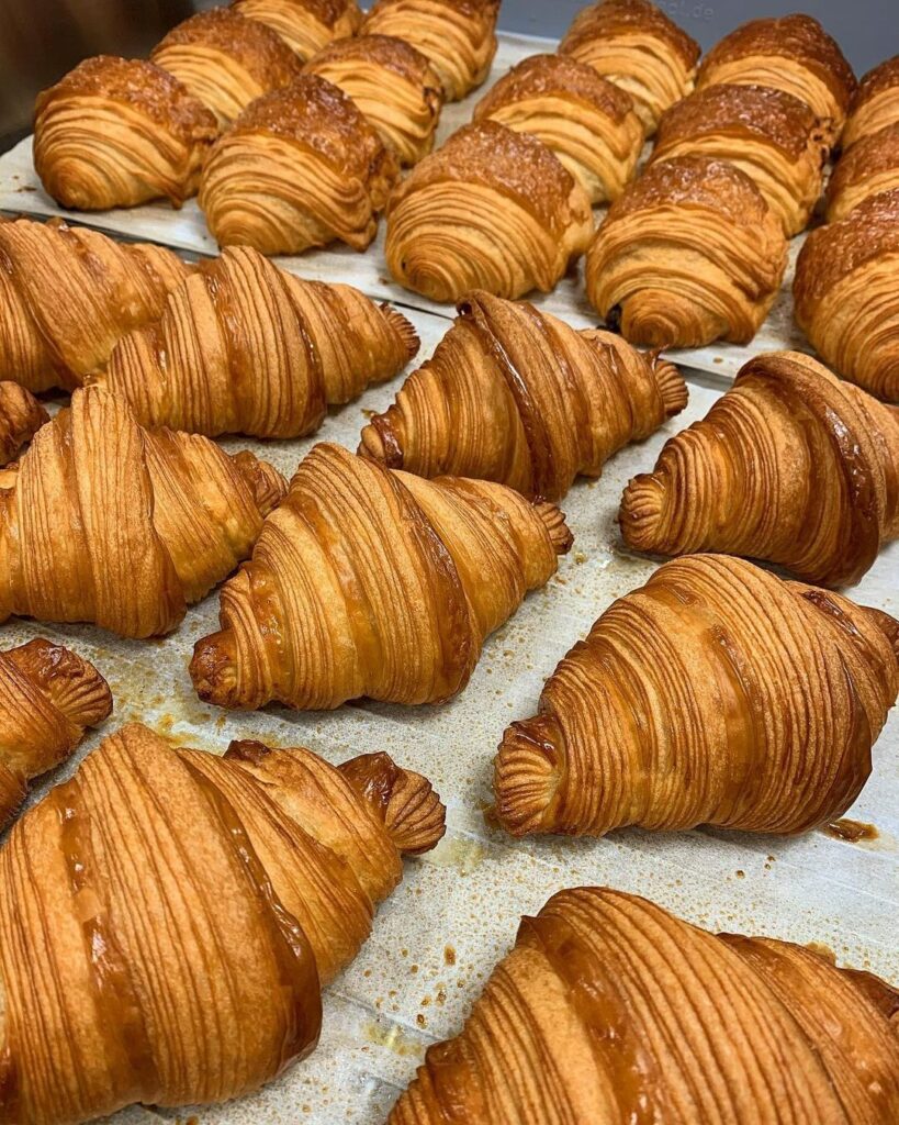 Freshly baked croissant and pains au chocolat coming out of the oven